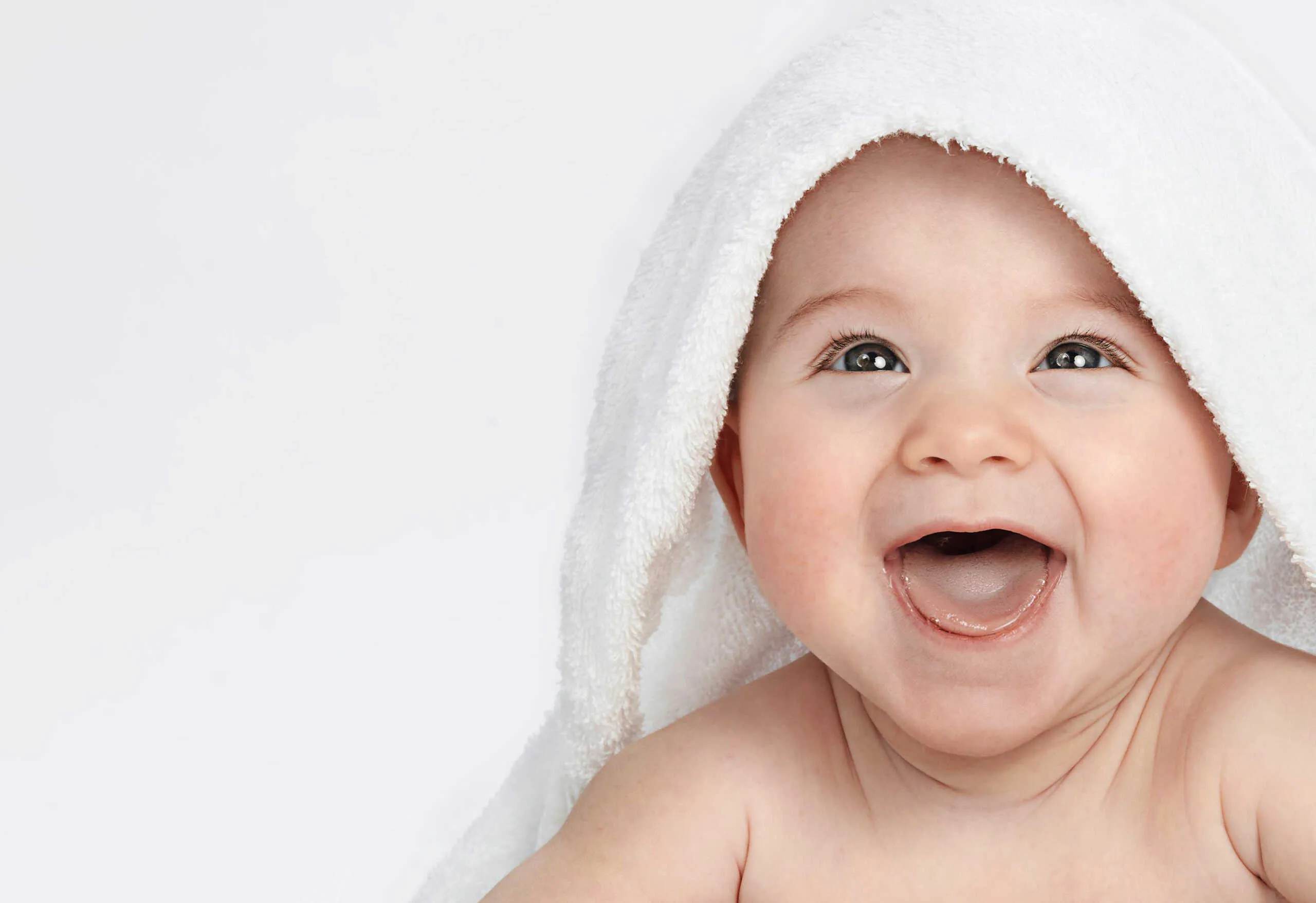 Smiling baby wrapped in a soft towel